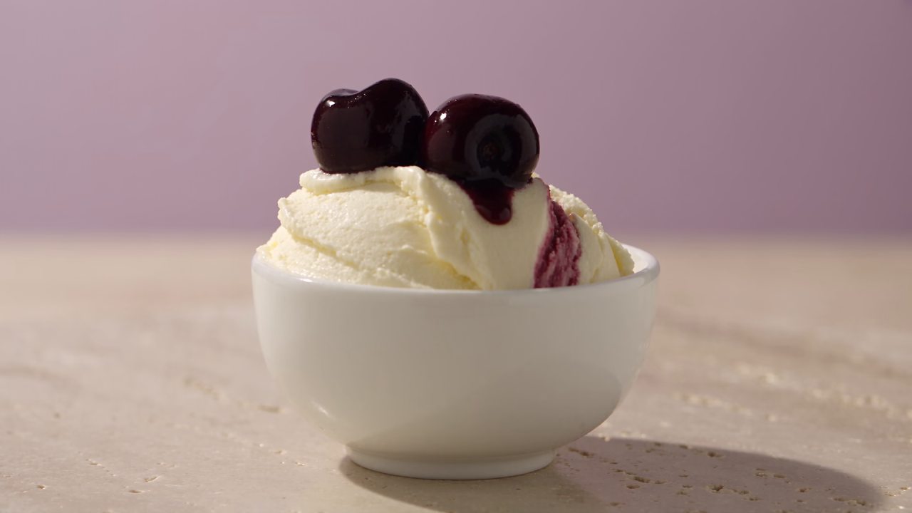 Vaniljev gelato z amarena višnjami in temno rdečim prelivom.