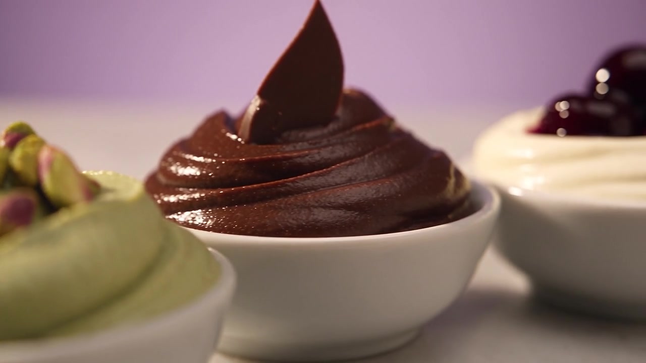 Pistacijev, čokoladni in mlečni gelato z amarena višnjami v treh posodicah.