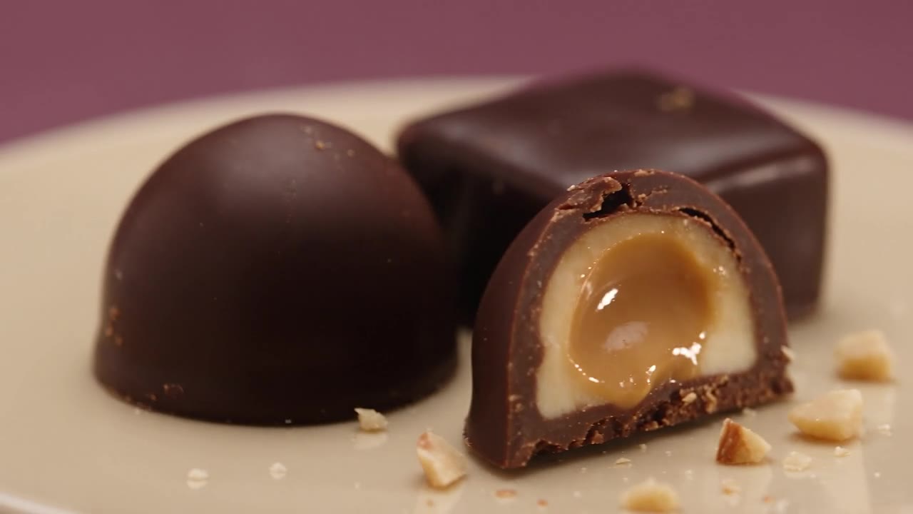 Čokoladne praline z nežno lešnikovo sredico na svetlem krožniku.